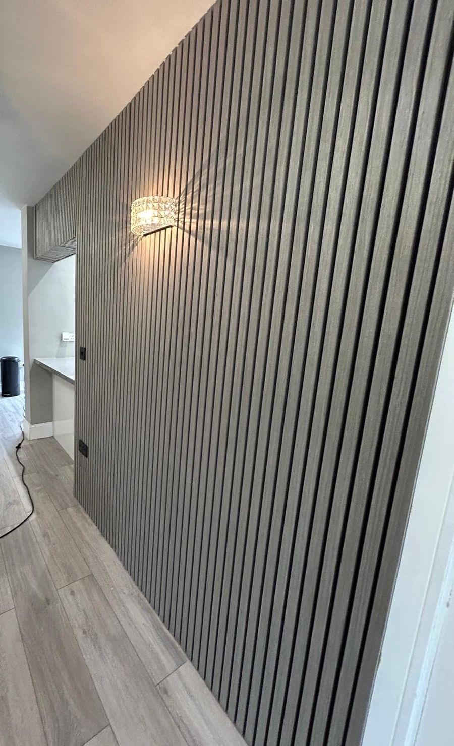 Dark slatted feature wall with a fitted wall light in a finished hallway