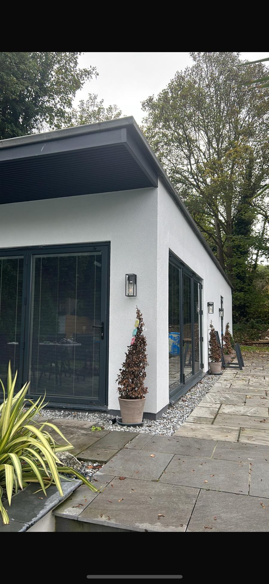 Modern rendered garden room with full height glazing and a paved approach